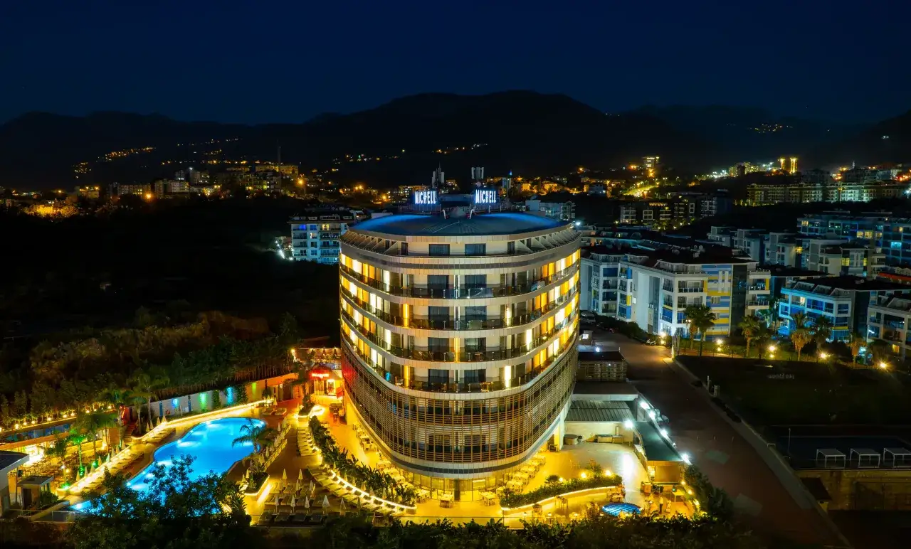 Nocny widok na lśniący hotel Michell z basenem i oświetlonymi pokojami. Wiele pozytywnych michell hotel spa opinie potwierdza jego urok.