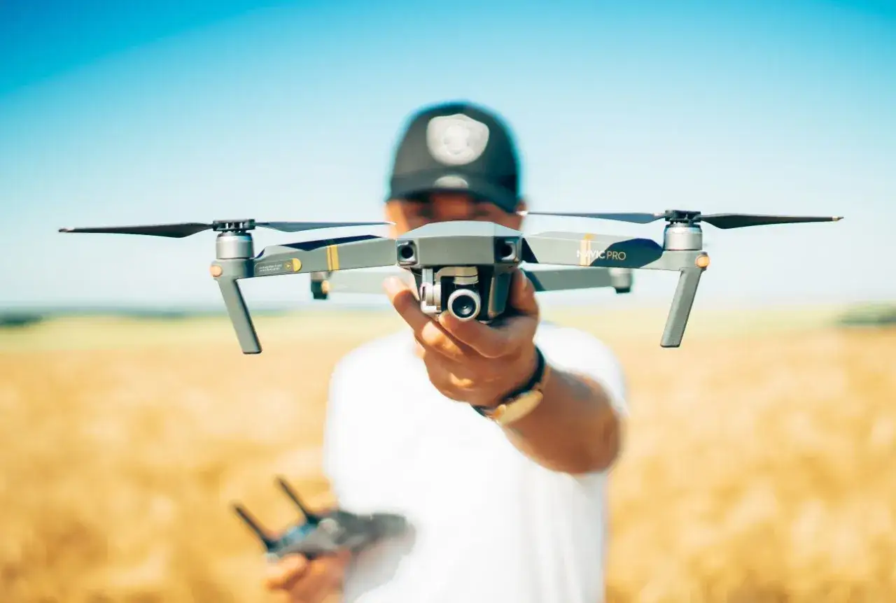 Mężczyzna trzyma drona Mavic Pro, idealnego dla początkujących. Ranking najlepszych dronów dla początkujących uwzględnia przepisy.
