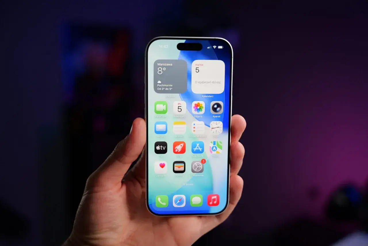 Dłoń trzyma iPhone'a z widocznymi ikonami aplikacji, w tym FaceTime. Może to być frustrujące, gdy FaceTime nie działa.