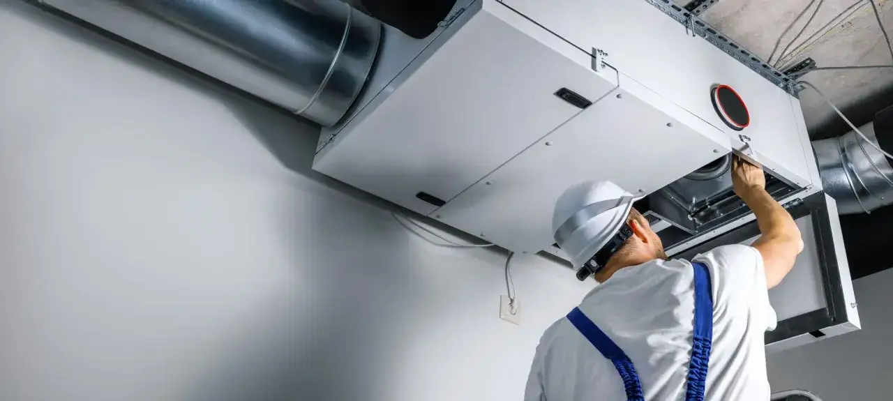 Technik sprawdza wentylację mechaniczną nawiewno-wywiewną. System zapewnia świeże powietrze w budynku.