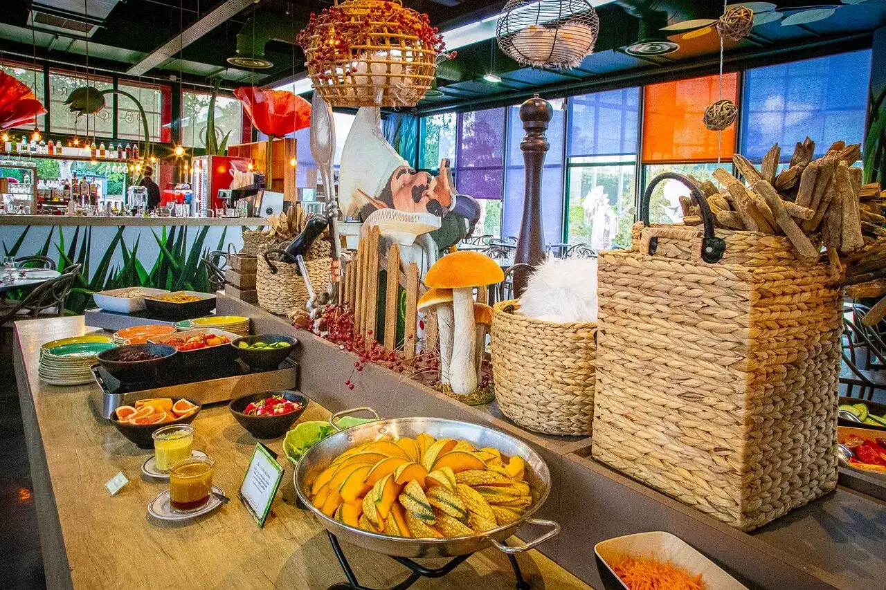 Buffet coloré avec des plats de courges, salades et fruits. Décoration ludique avec des champignons et un personnage de conte de fées, dans l'ambiance du resto Futuroscope.
