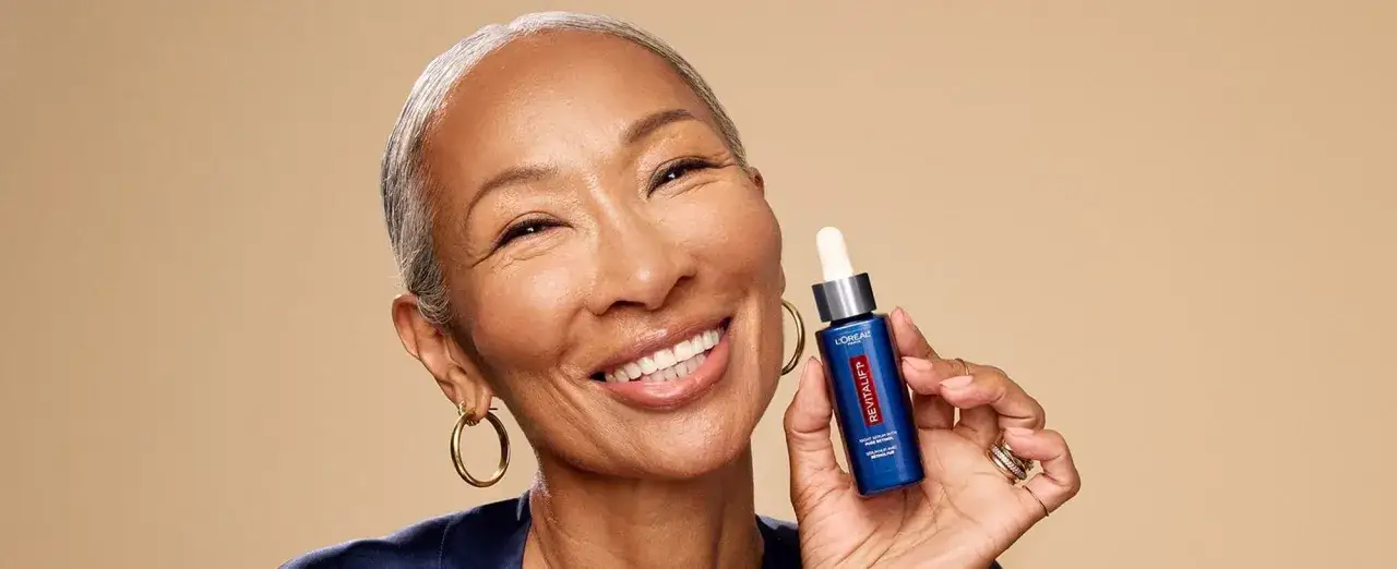 Mujer sonriente muestra un sérum Revitalift con retinol, ideal para rejuvenecer la piel y combatir arrugas.