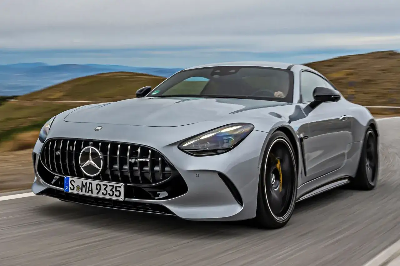 Srebrny Mercedes GT 63 AMG pędzi po krętej drodze, ukazując swoją sportową sylwetkę na tle górskiego krajobrazu.