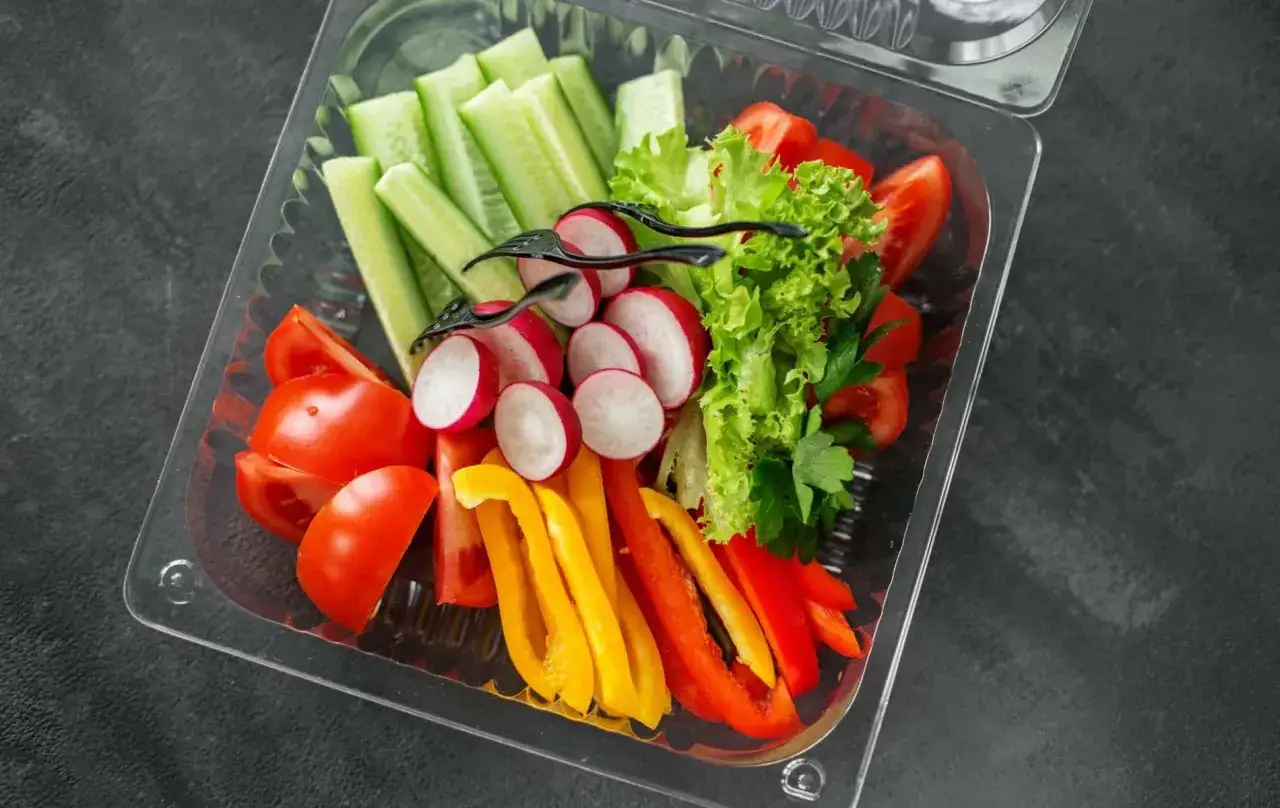 Świeże warzywa w pudełku – idealne na start, gdy zastanawiasz się, jak otworzyć catering dietetyczny. Pomidory, ogórki, rzodkiewki, papryka i sałata.