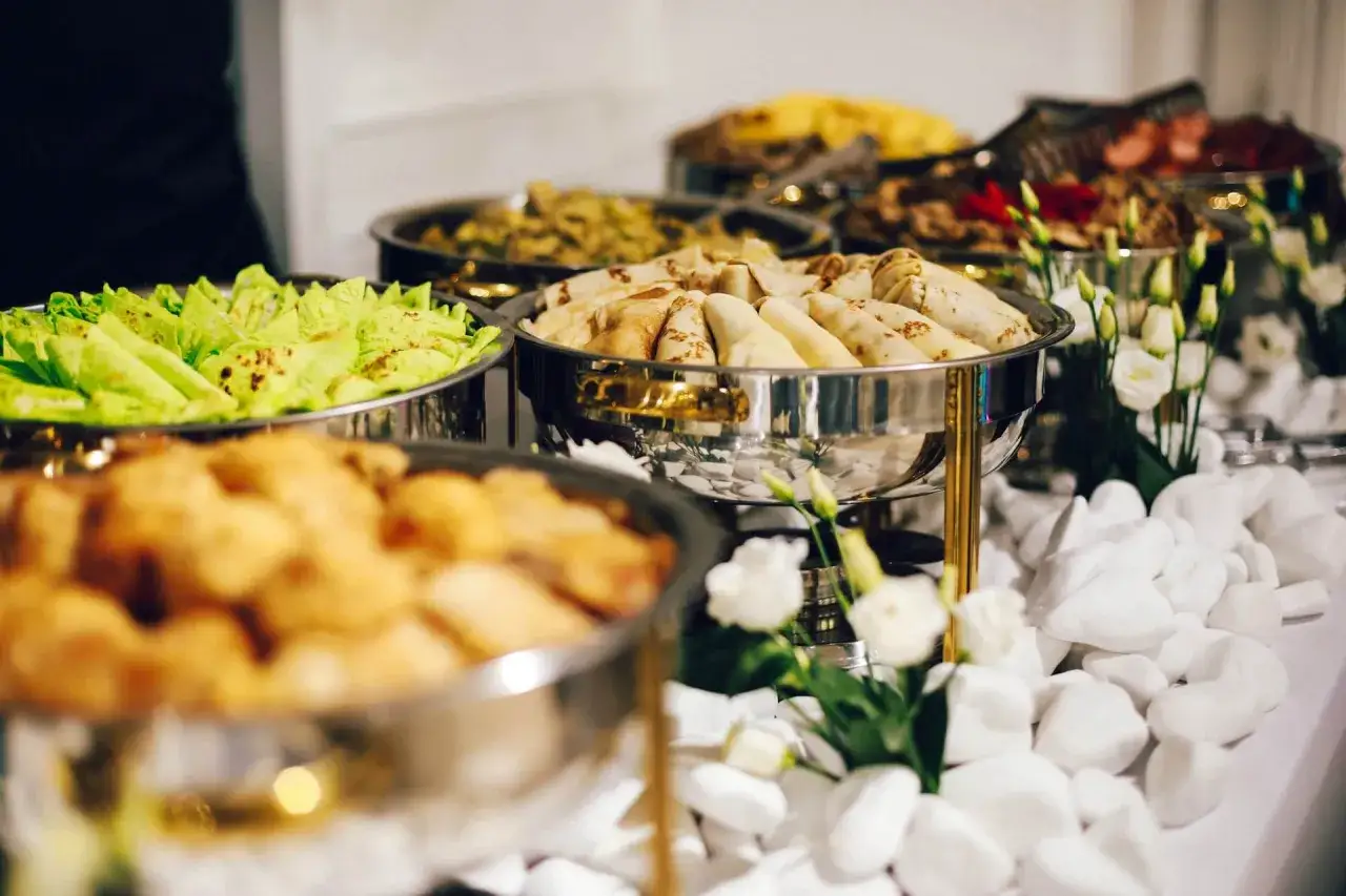 Bufet z jedzeniem: naleśniki, sałatka, smażone kąski. Zastanawiasz się, ile kosztuje catering na imprezę?