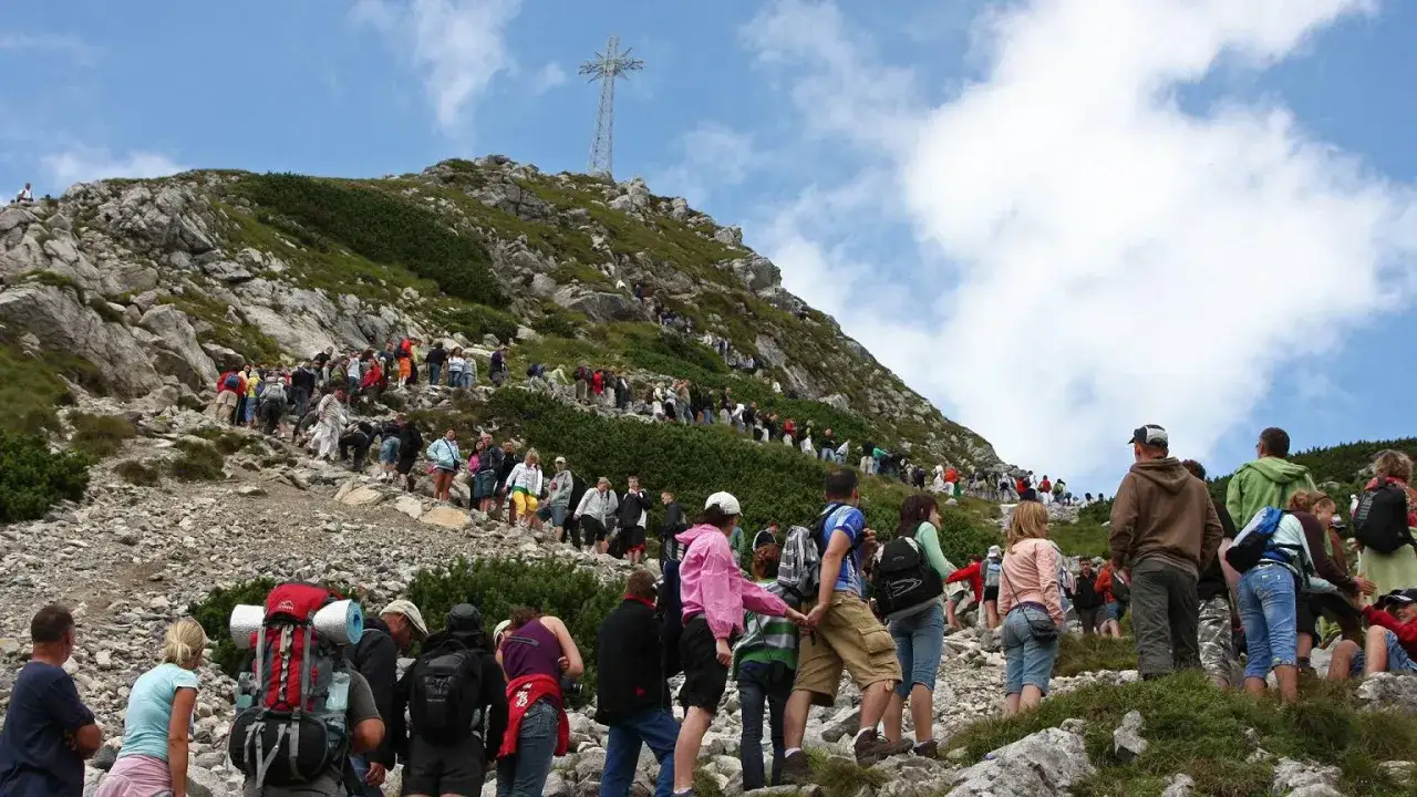 Tłum turystów wspina się na Giewont. Trasa z Kasprowego na Giewont jest długa, ale widok z góry wynagradza wysiłek.