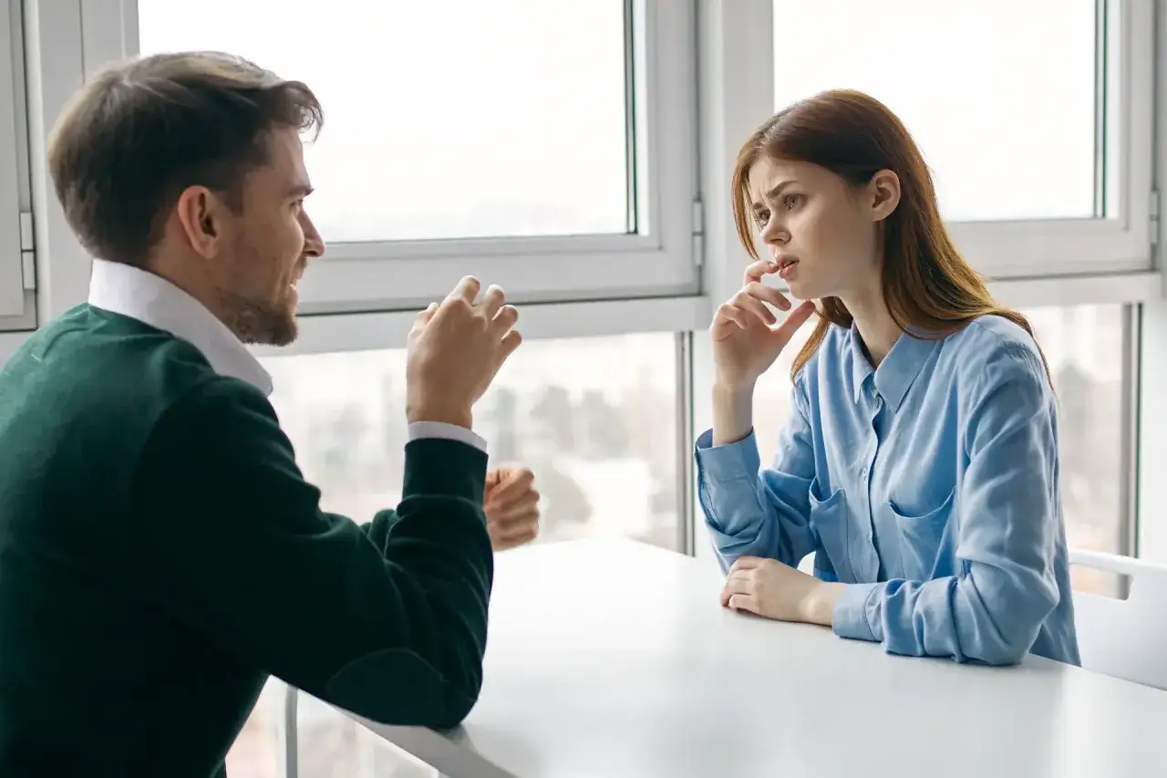 Mężczyzna tłumaczy kobiecie, jak przeprowadzić rozmowę oceniającą z trudnym pracownikiem. Kobieta słucha z uwagą, zamyślona.