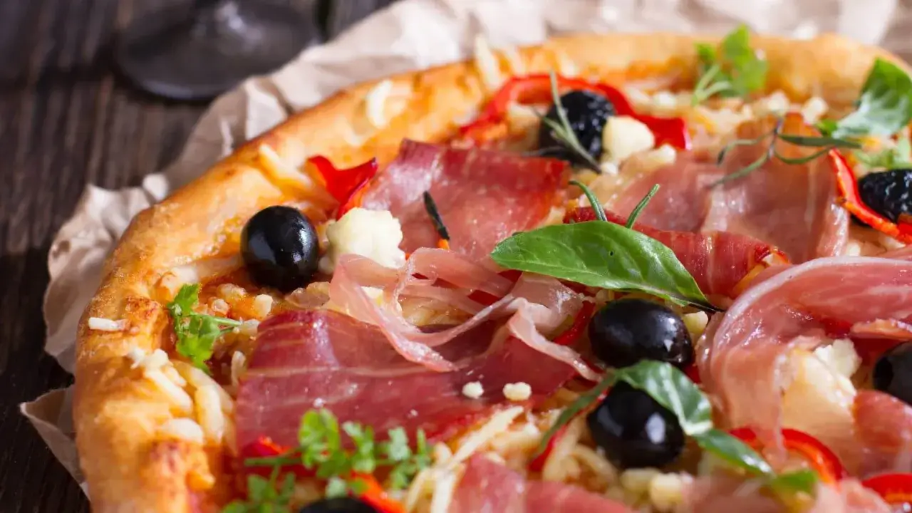 Pyszna pizza z cienko pokrojoną, aromatyczną szynką, czarnymi oliwkami i papryką. Idealna na każdą okazję, zastanawiasz się jaka szynka na pizzę będzie najlepsza? Ta wygląda wyśmienicie!