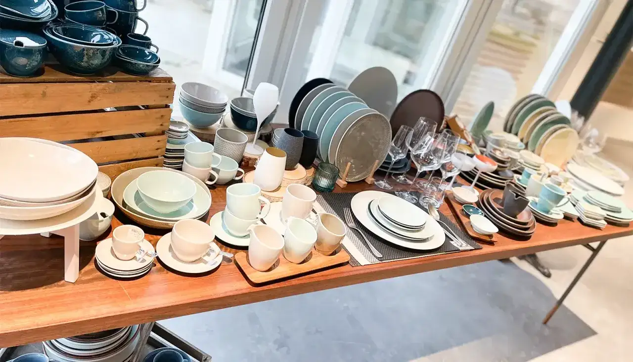 Vielfältiges Gastronomiegeschirr aus Keramik und Glas, darunter Teller, Schüsseln, Tassen und Gläser.