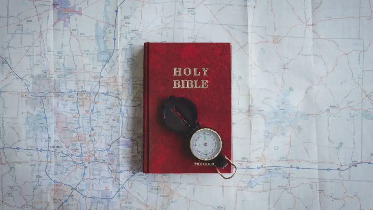 Czerwona Biblia i kompas na mapie. Pismo Święte wskazuje drogę, jak nie cudzołożyć, co to znaczy żyć w zgodzie z Bogiem.