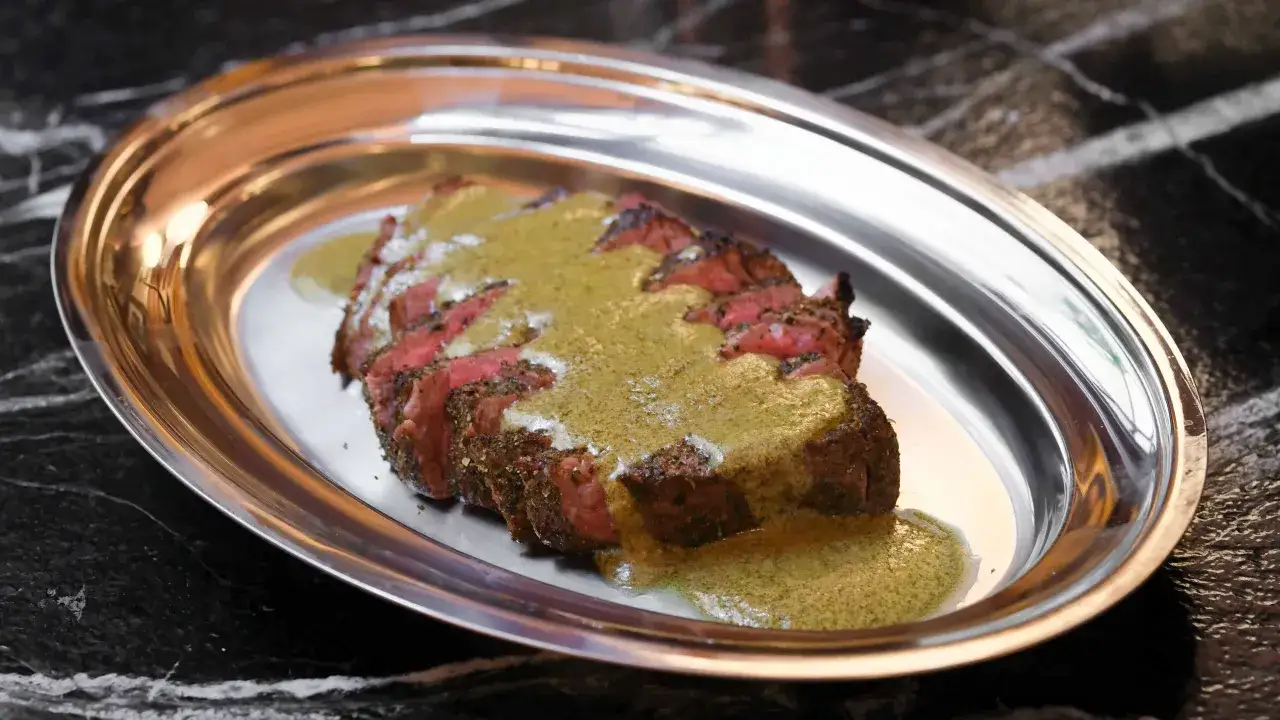 Tranché de bœuf, nappé d'une sauce verte, une spécialité parisienne servie sur un plateau métallique.