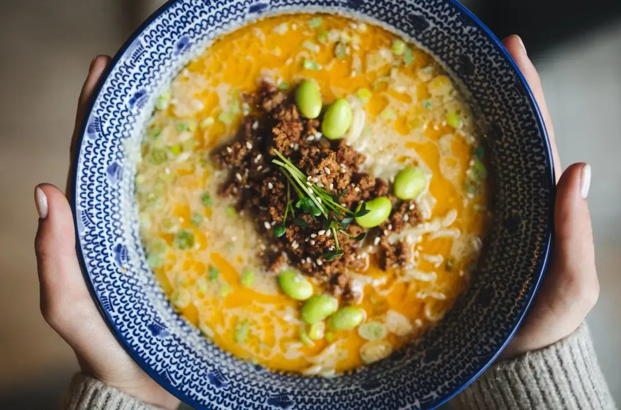 Miseczka tantanmen z mielonym mięsem, edamame i szczypiorkiem.