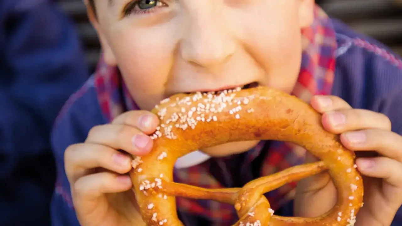 Un enfant savoure une bretzel, une spécialité alsace, avec délice.
