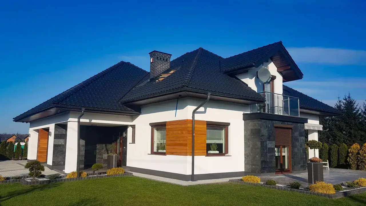 Nowoczesny dom z grafitowym dachem i oknami w kolorze złoty dąb. Elewacja biała z kamiennymi akcentami.
