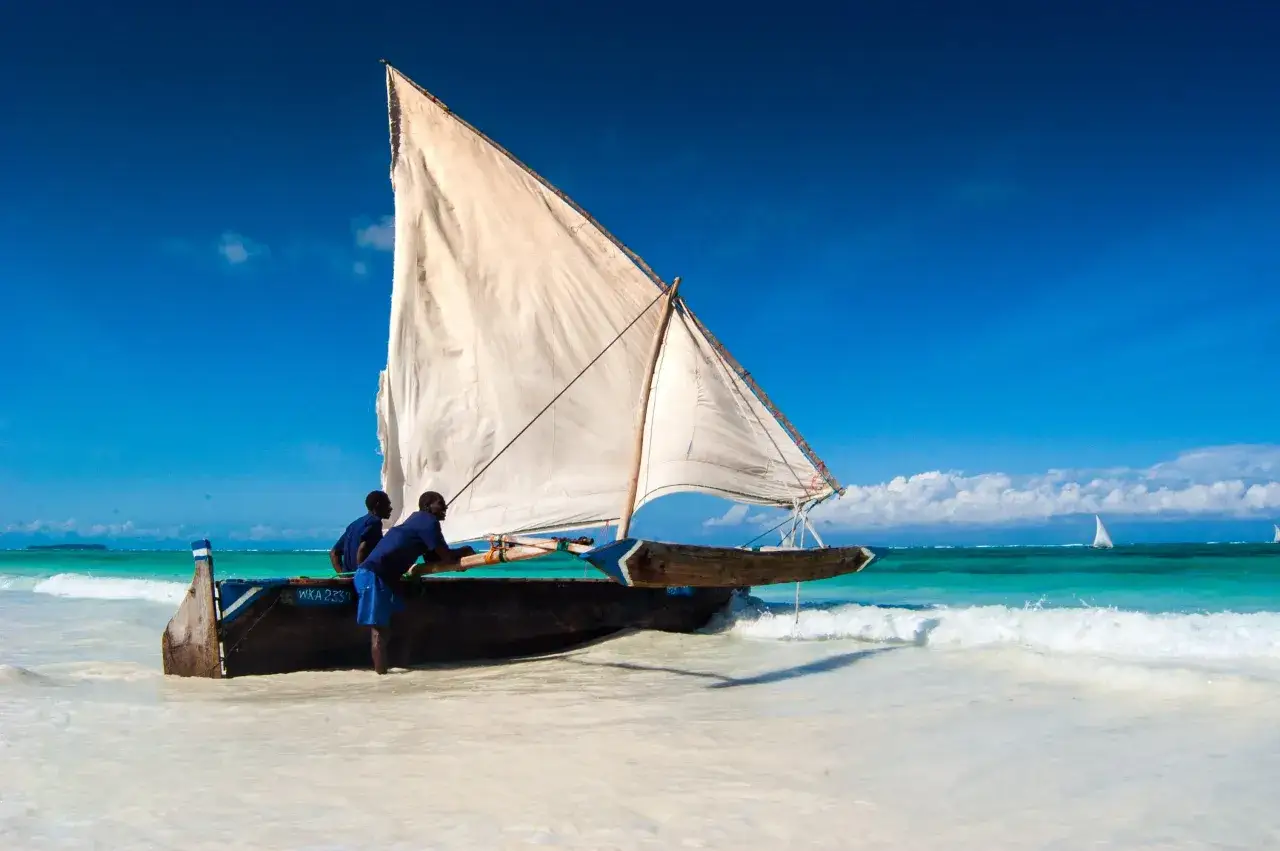 Dwaj mężczyźni przygotowują tradycyjną łódź do rejsu. Marzysz o podróży? Sprawdź, ile się leci na Zanzibar z Poznania!
