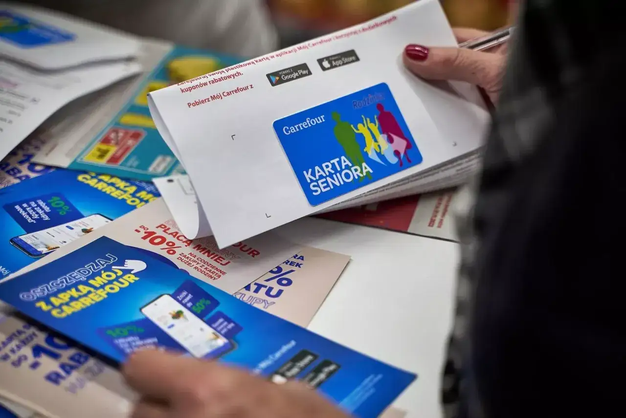 Karta Seniora Carrefour daje zniżki i rabaty. Na zdjęciu widać ulotki i kartę z logo Carrefour.