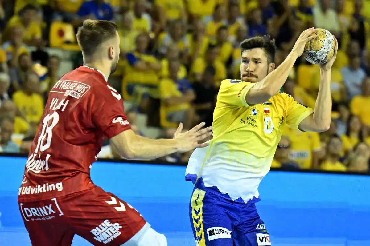 Piłkarz Aalborg Handball w żółtej koszulce rzuca piłkę, obok zawodnik w czerwonej.
