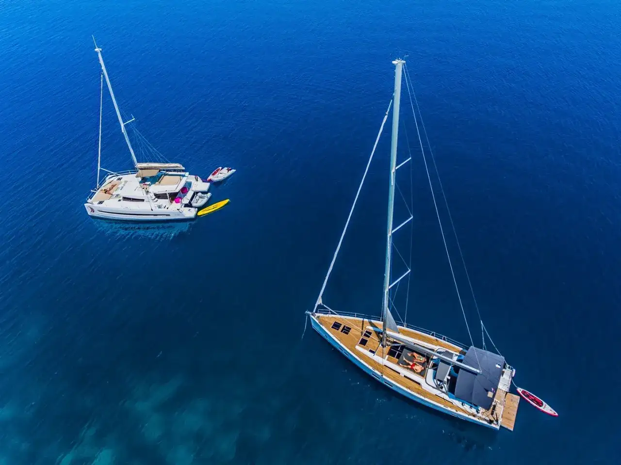 Zwei Segelboote, ein Katamaran und eine Yacht, liegen friedlich auf dem tiefblauen Meer.