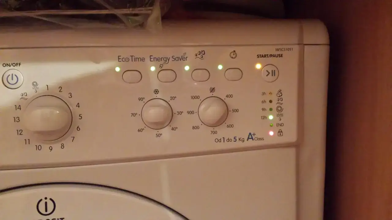 Panel sterowania pralki Indesit z podświetlonymi wskaźnikami i pokrętłami programów.