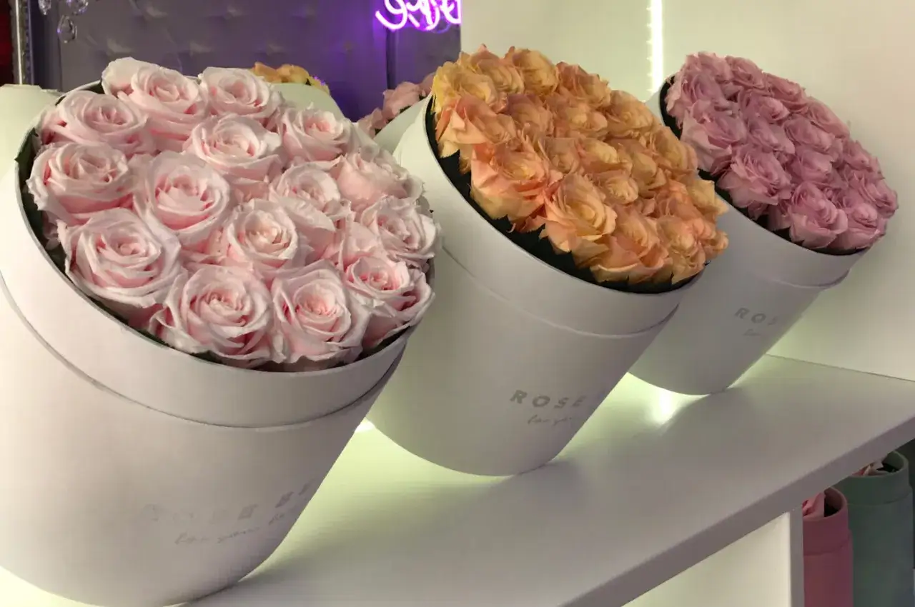 Trzy okrągłe pudełka z różami w pastelowych kolorach: różowym, brzoskwiniowym i fioletowym. Idealne kwiaty na ślub w prezencie.
