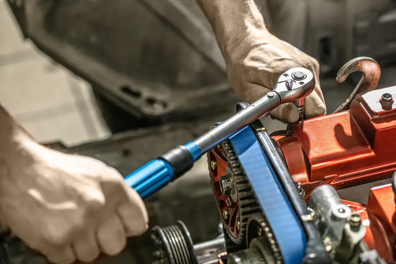 Mechanik używa klucza dynamometrycznego do świec, precyzyjnie dokręcając element silnika.