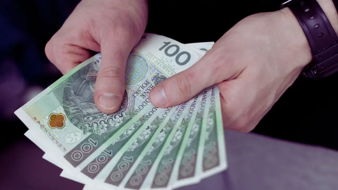 Dłonie trzymają stos banknotów 100 zł. Czy to wypłata z UoP?