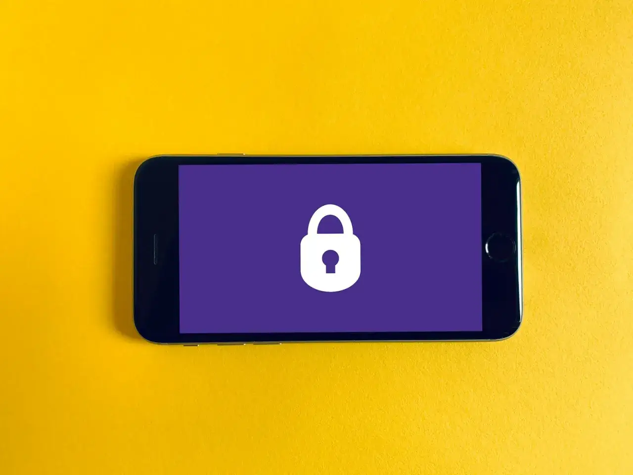 Smartfon z ikoną kłódki na fioletowym tle, symbolizującą wzory blokady telefonu i bezpieczeństwo danych.