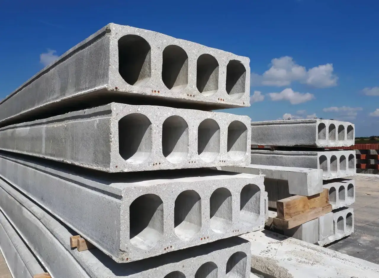 Stos betonowych płyt stropowych kanałowych pod błękitnym niebem. Gotowe do budowy domu.