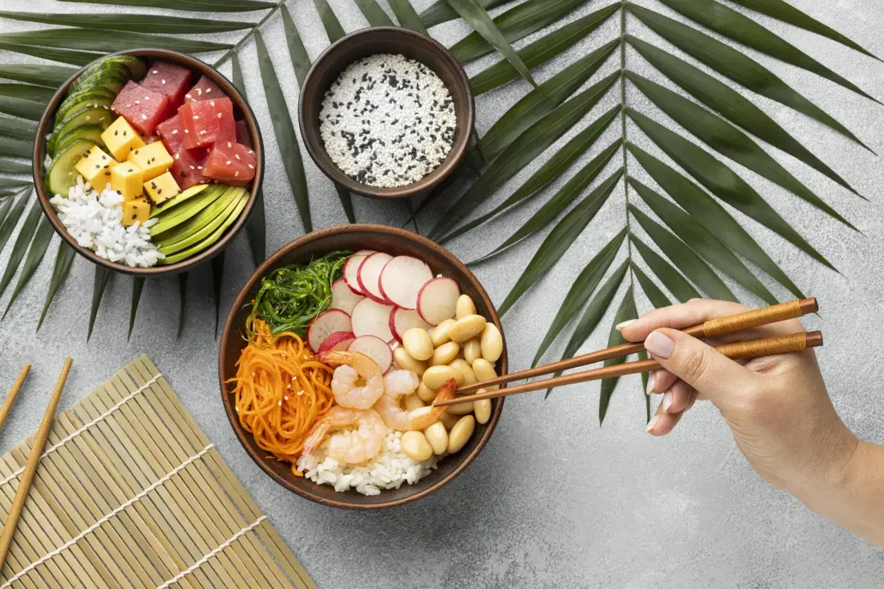 Dwie miski z pysznym sushi: jedna z tuńczykiem, awokado i ogórkiem, druga z krewetkami, fasolką i warzywami.