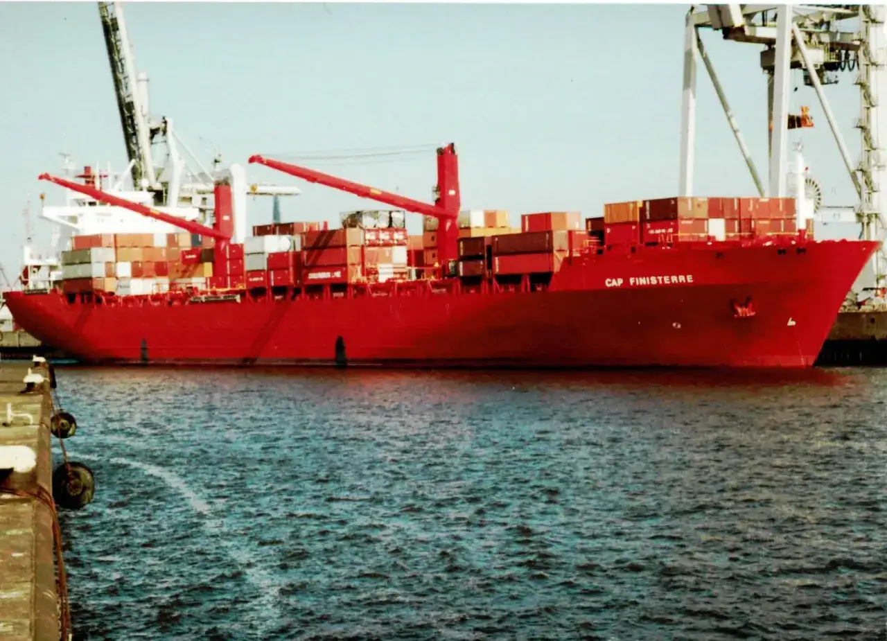 Rotes Containerschiff "Cap Finisterre" im Hafen, beladen mit vielen Containern, Kräne im Hintergrund.