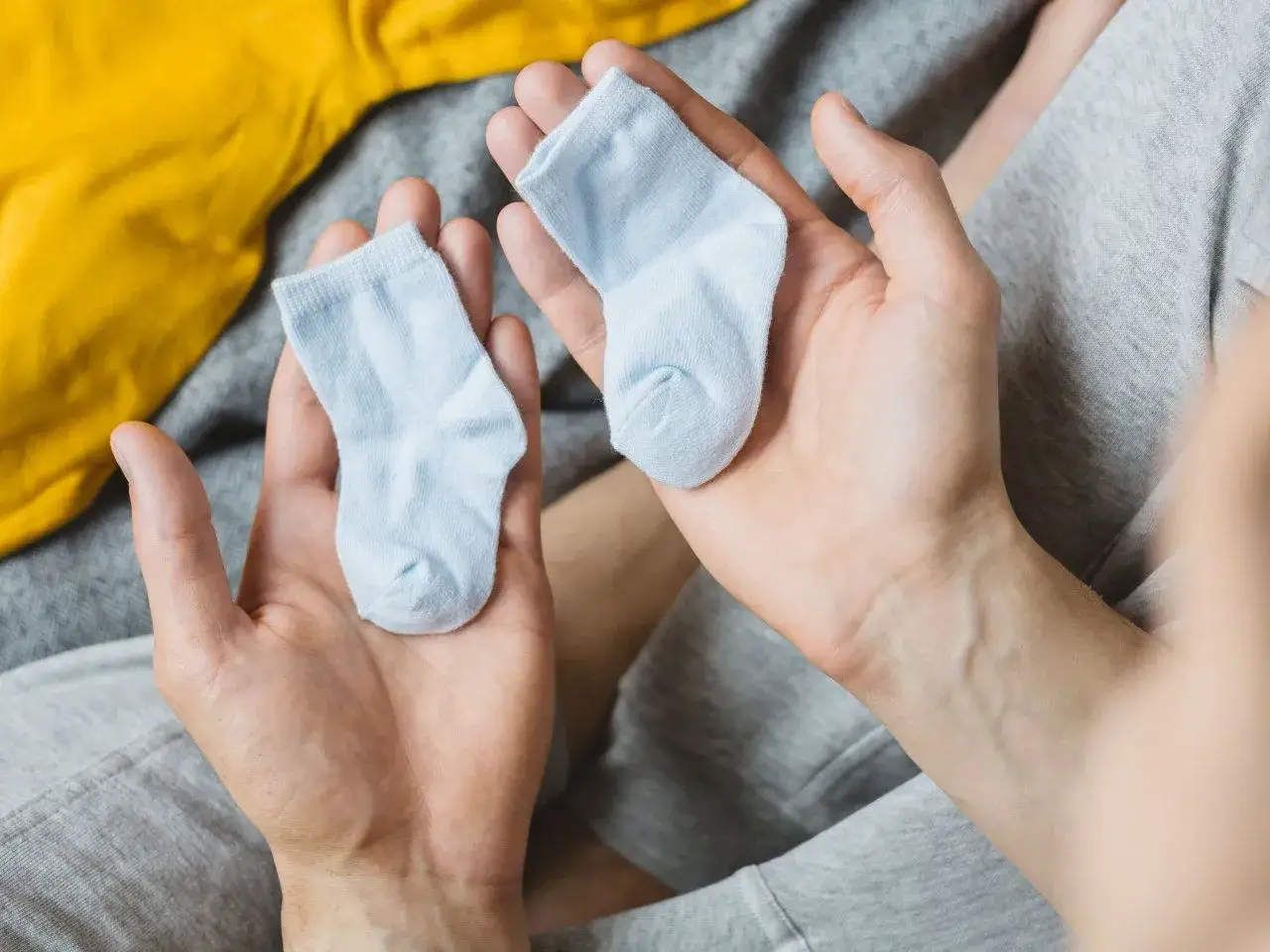 Dwie maleńkie, błękitne skarpetki w dłoniach. Zastanawiasz się, jaki rozmiar skarpetek dla noworodka będzie najlepszy?
