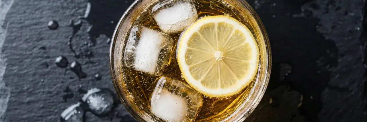 Orzeźwiający whiskey z tonikiem, z plastrem cytryny i kostkami lodu, na ciemnym tle.