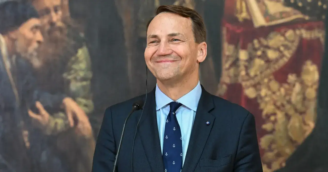 Uśmiechnięty Sikorski, który polityk? W tle obraz z postaciami.