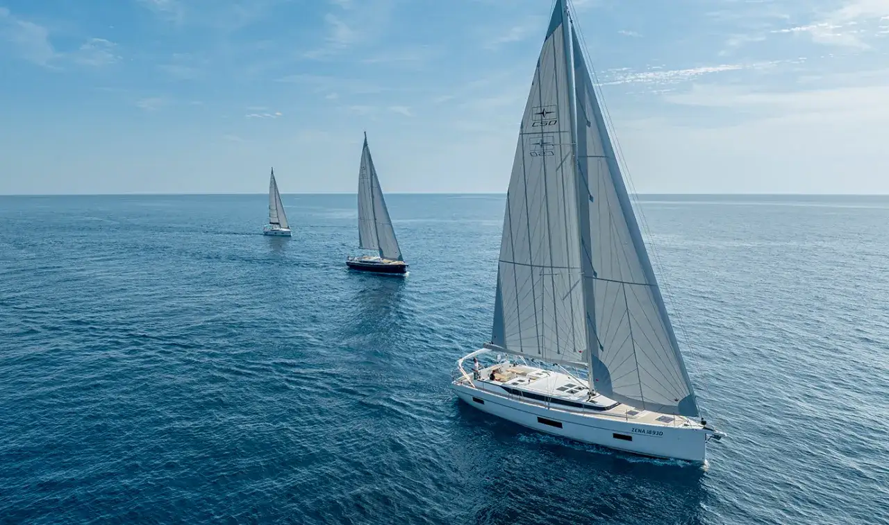 Drei weiße Segelboote segeln auf dem blauen Meer. Die Kosten für ein Segelboot wie dieses sind hoch, aber das Erlebnis unbezahlbar.