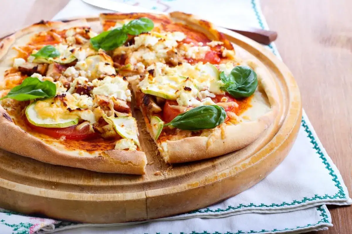 Pizza dla cukrzyka z kurczakiem, cukinią i fetą, ozdobiona bazylią. Zdrowa i smaczna alternatywa dla tradycyjnej pizzy.