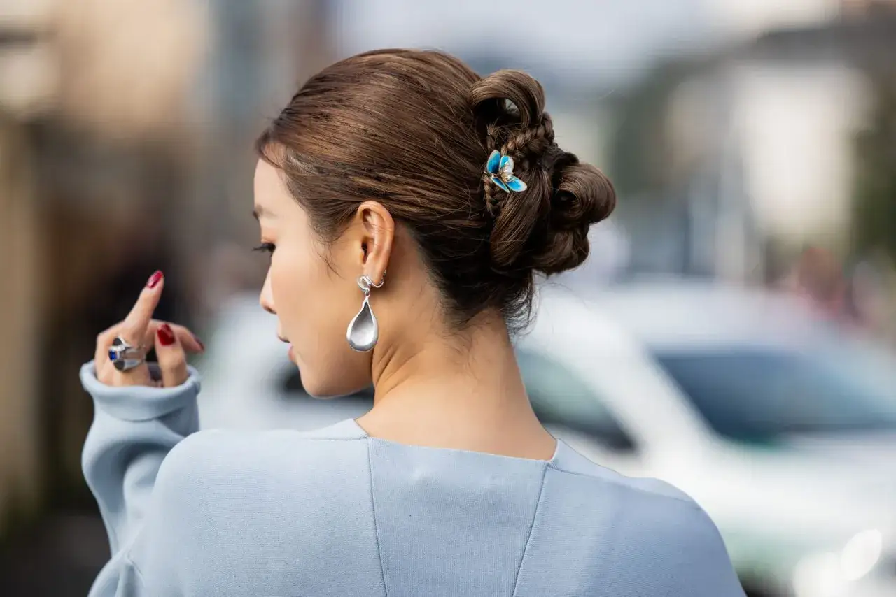 Peinado recogido con trenzas y moños, adornado con un pasador de mariposa. Un look de recogidos sencillos y elegantes.