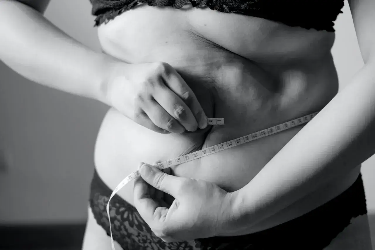 Kobieta mierzy talię centymetrem, szukając sposobu, jak schudnąć 5 kg w 3 dni.