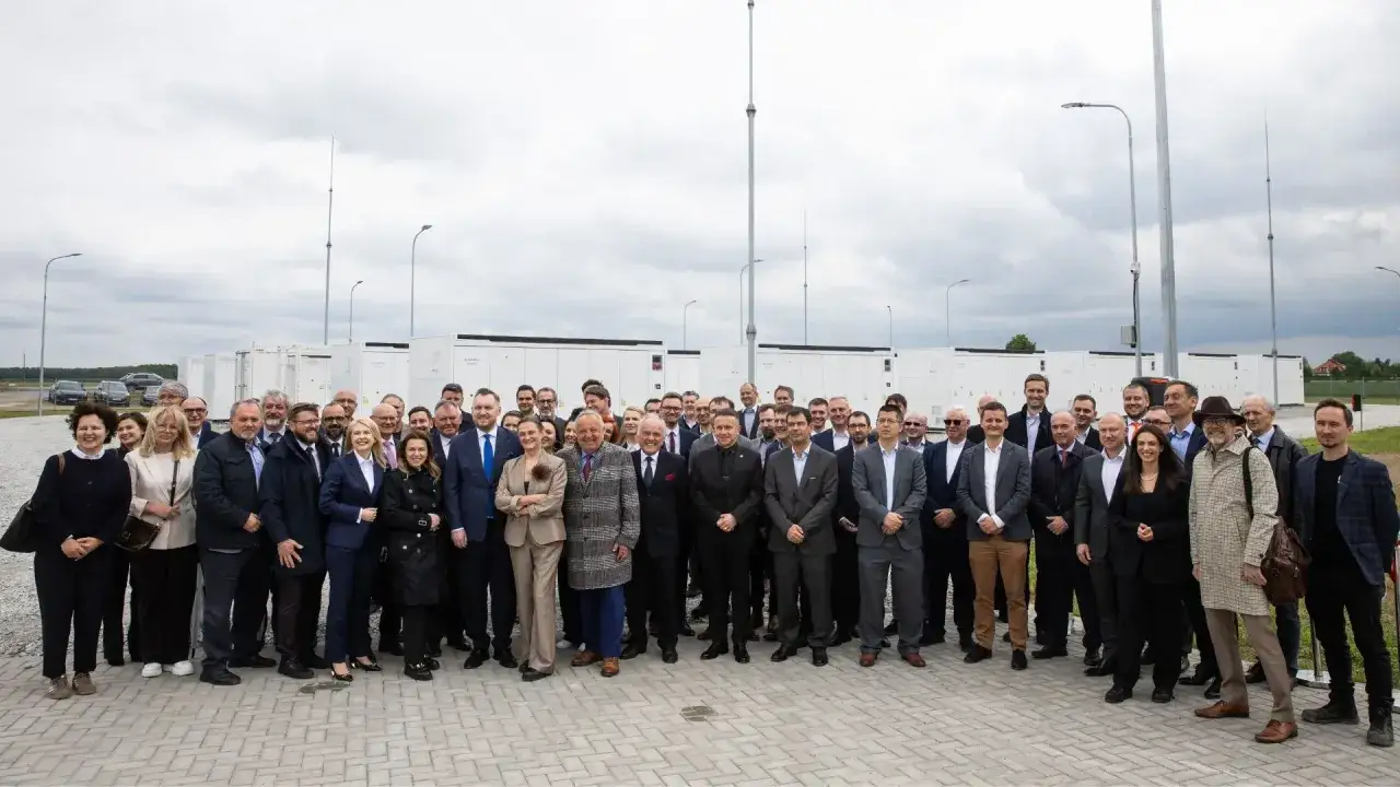 Grupa osób przed bateryjnymi magazynami energii, symbolizującymi rozwój polskiego stowarzyszenia magazynowania energii.