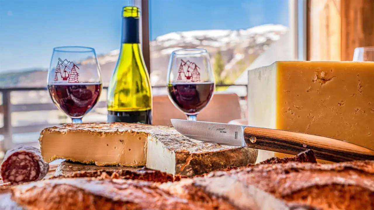 Dégustation de fromages et vin rouge, un aperçu de la gastronomie auvergnate avec vue sur les montagnes enneigées.