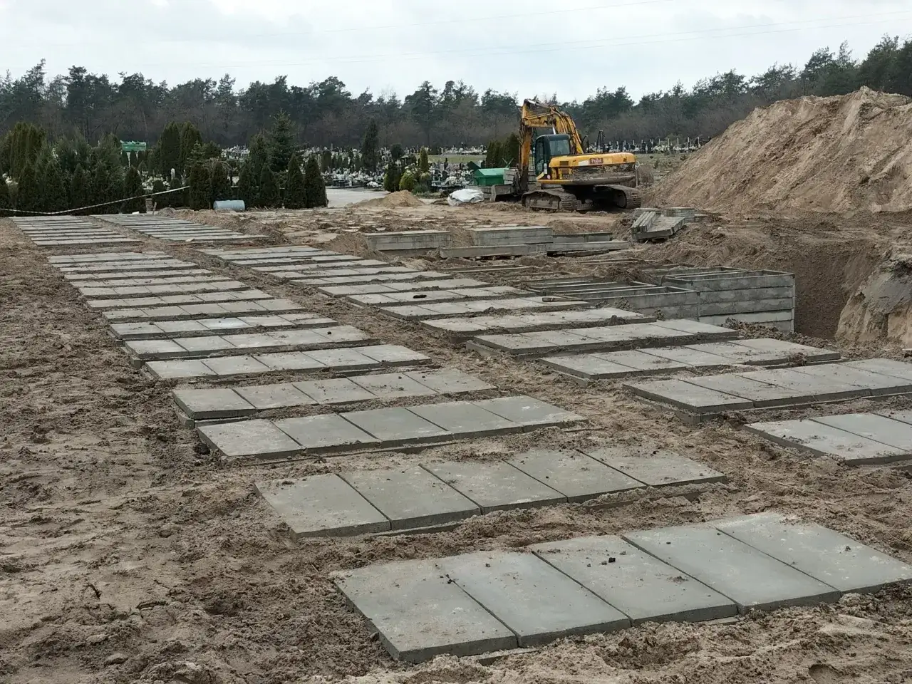 Przygotowanie terenu na cmentarzu, gdzie układane są płyty betonowe. Zastanawiasz się, ile kosztuje fundament pod pomnik? Tu widać początek prac.