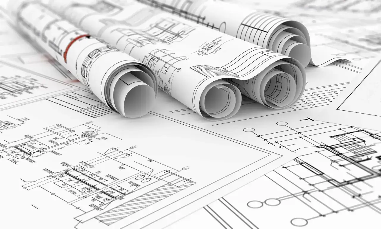 Zwoje dokumentacji technicznej, ukazujące szczegółowe plany budowlane. To projekt zamienny po zakończeniu budowy, gotowy do analizy.