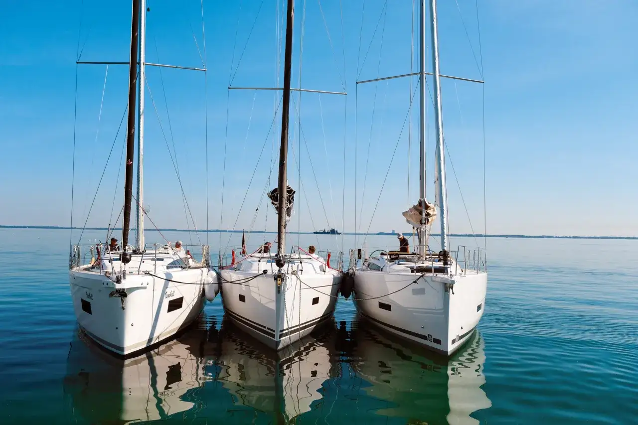 Drei weiße Segelyachten liegen nebeneinander im ruhigen Wasser. Ein Blick auf die elegante Bauweise, wie sie nur ein renommierter segelyacht hersteller hervorbringen kann.
