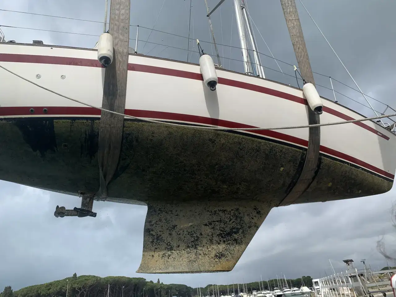 Segelboot wird angehoben, der Rumpf ist mit Algen bedeckt und bereit für die Behandlung mit Epoxidharz zum Streichen.