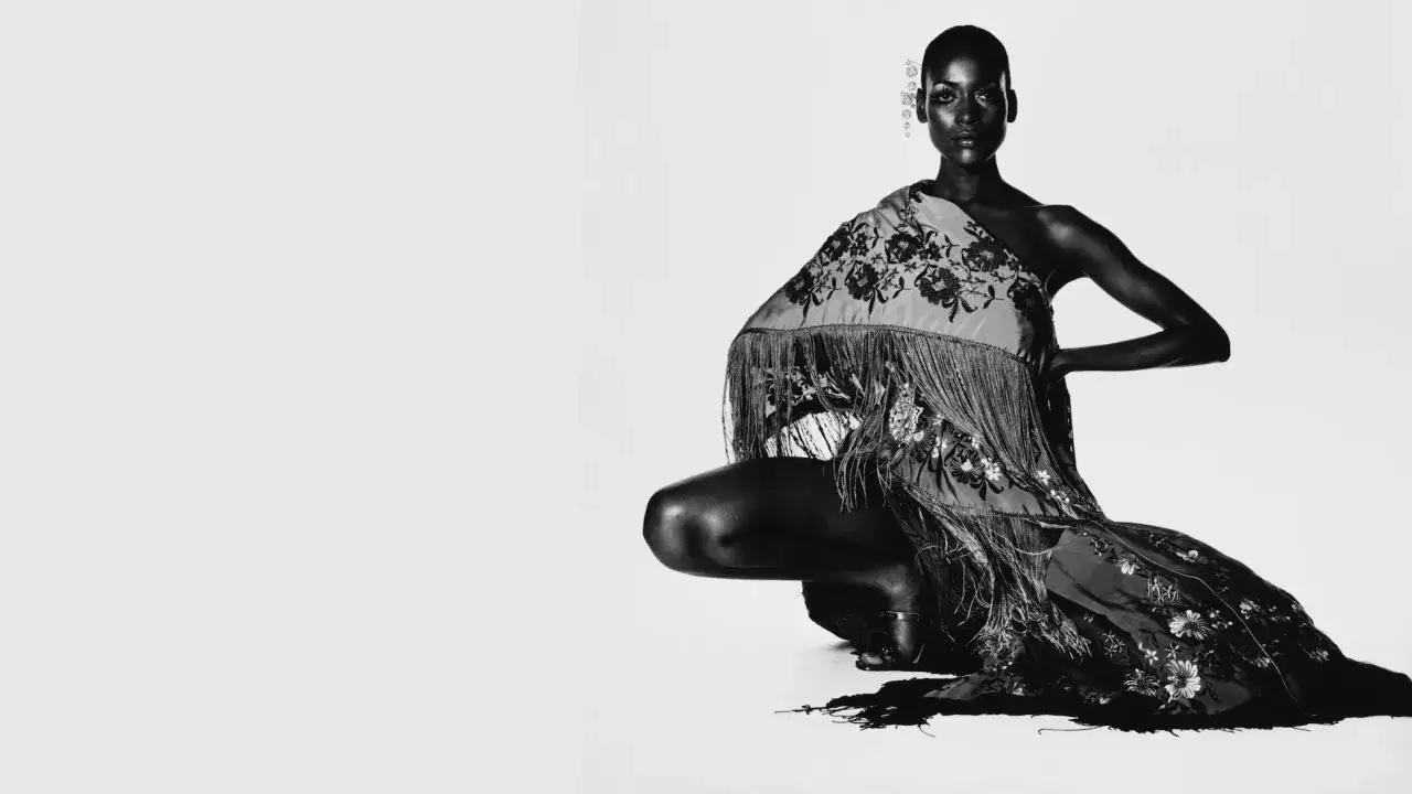 Irving Penn captura a una modelo agachada con un chal bordado y flecos.