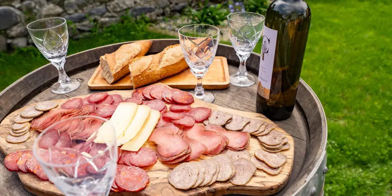 Plateau de charcuterie et fromage, pain frais, verres et bouteille de vin, une spécialité culinaire des Pyrénées.