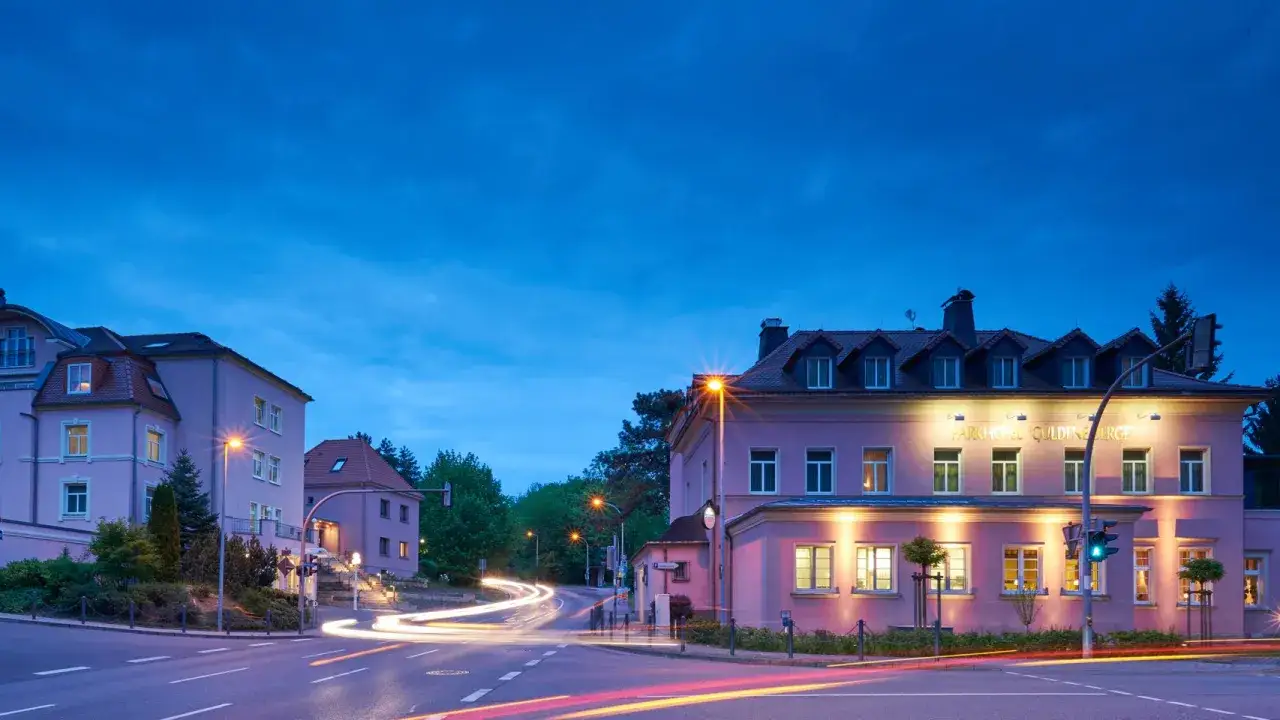 Parkhotel Güldene Berge in Harz bei Nacht, mit Lichtern und Spuren von Autos.