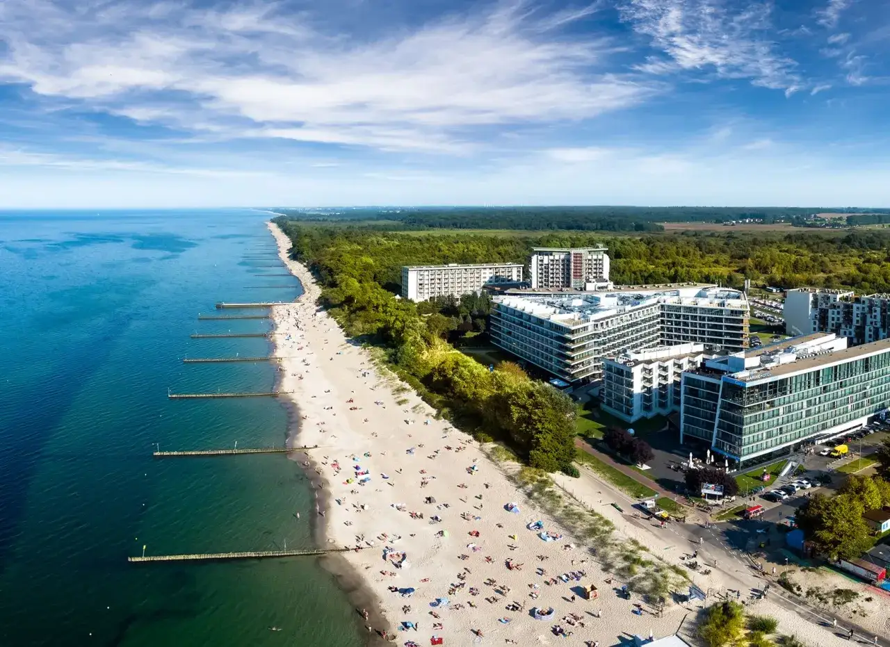 Widok z lotu ptaka na plażę nad Bałtykiem z hotelami i turystami.