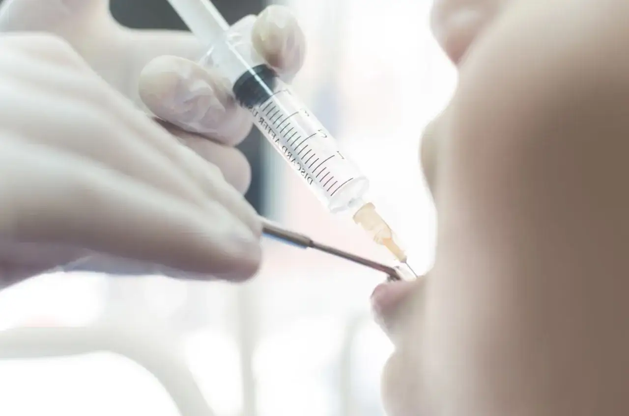 Dentysta podaje znieczulenie pacjentowi strzykawką.