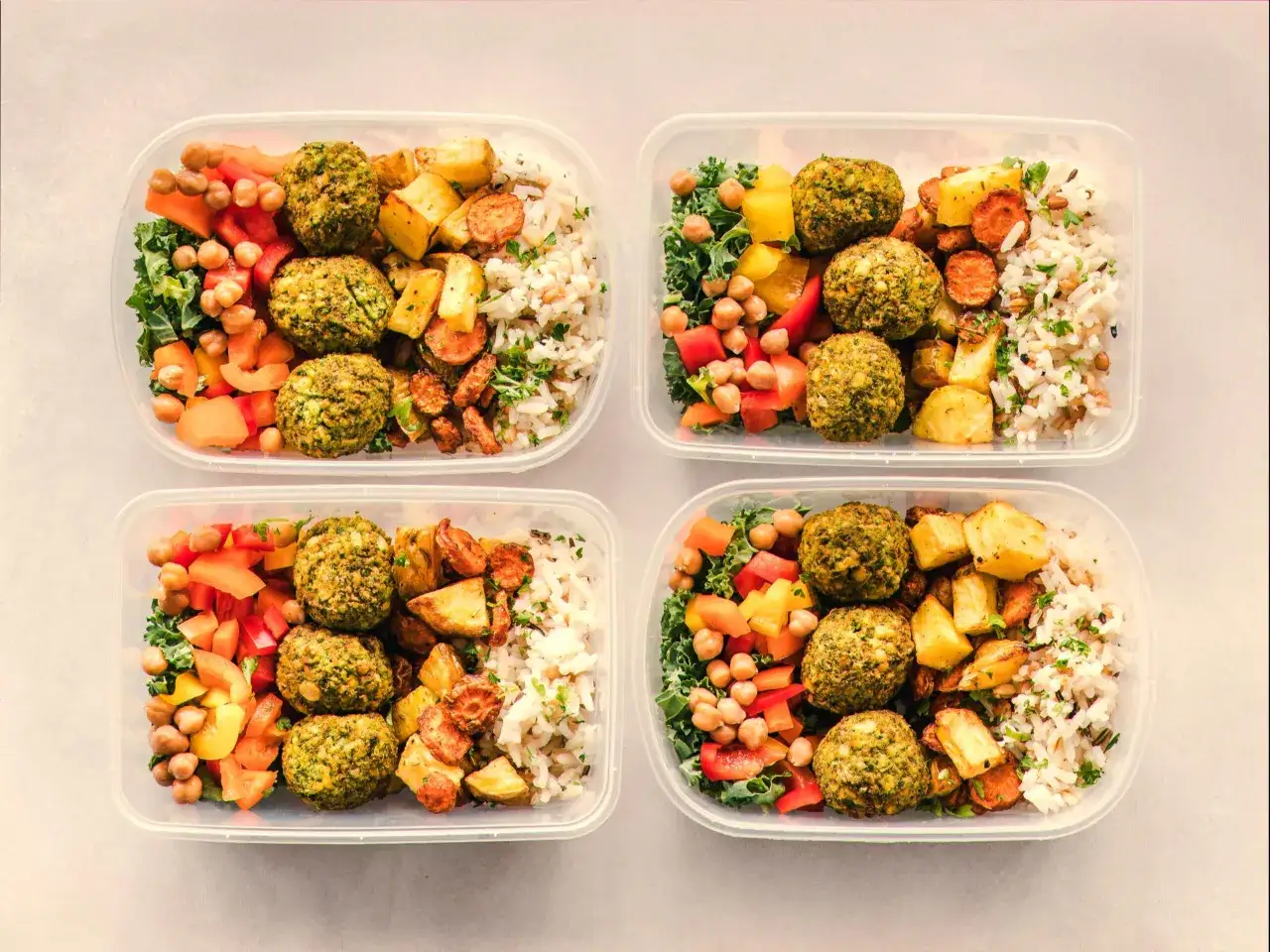 Cztery pojemniki z posiłkami: falafel, ryż, pieczone warzywa i sałatka. Idealny jadłospis na dietę dobrych produktów.