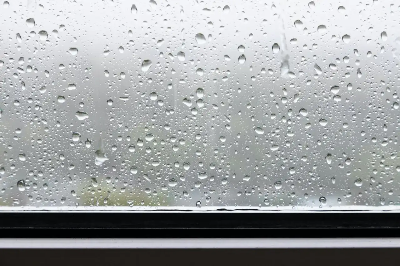 Krople deszczu na szybie, tworzące naturalny wzór. Jak wyciszyć parapet przed deszczem? Może warto po prostu cieszyć się widokiem?